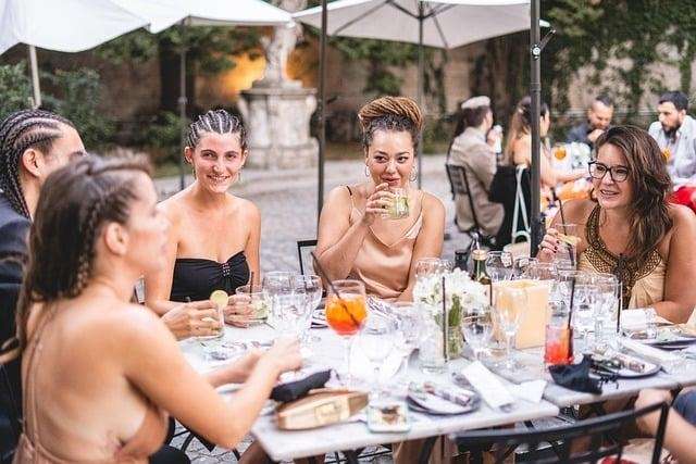 A group of elegantly dressed women seated at an outdoor restaurant table.